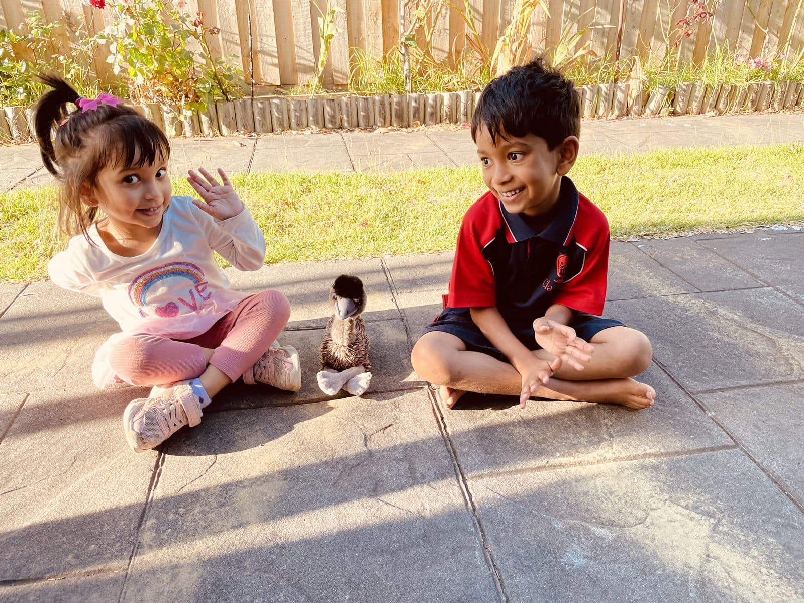 My two kids sitting cross-legged on the patio in the afternoon sun after the school run.